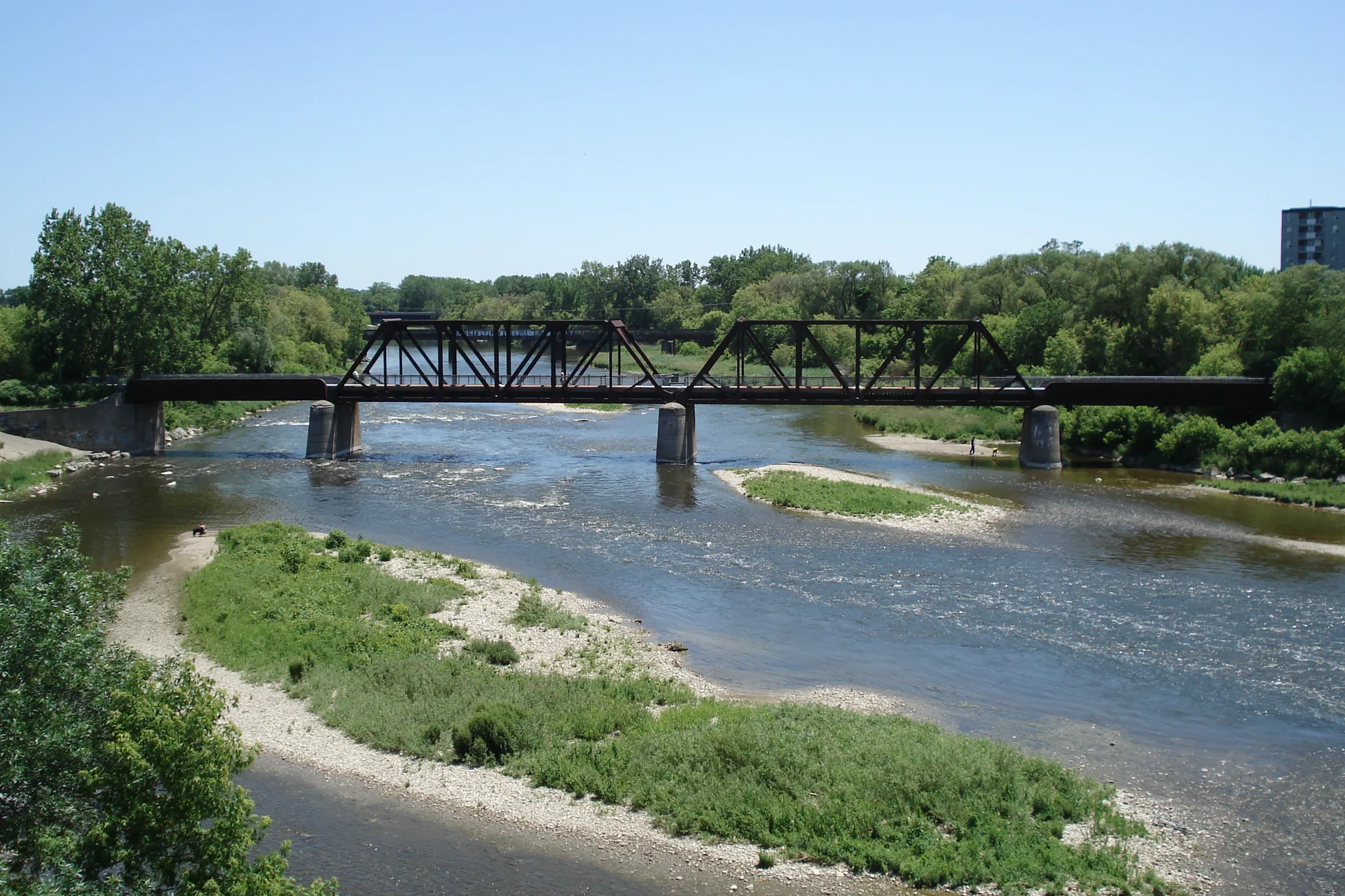 The Grand River in Brantford with the railway truss bridge, green banks and riverside trails on a summer day