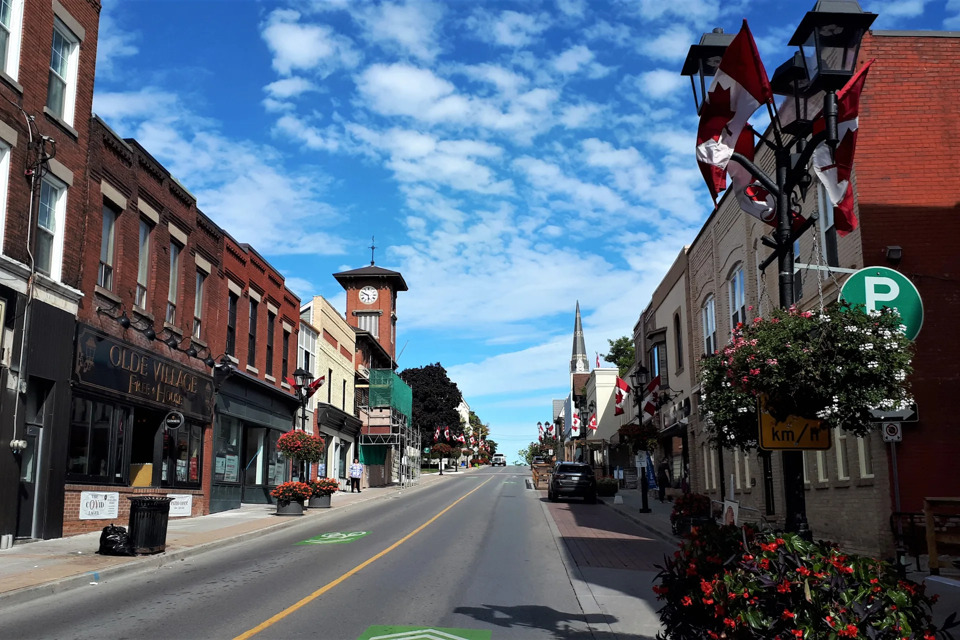 Newmarket business owner standing on historic Main Street with the clock tower and storefronts behind on a bright morning