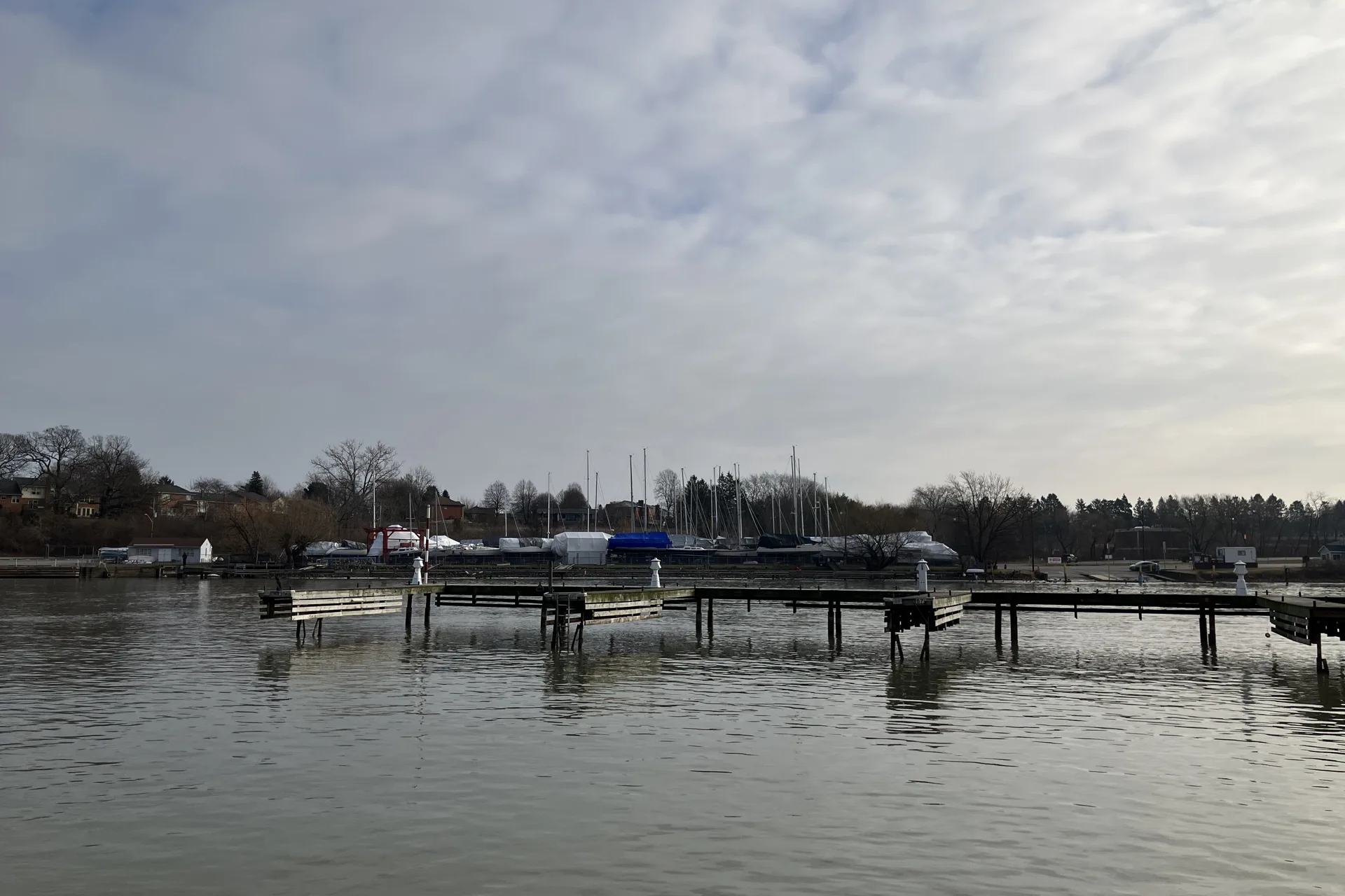 The harbour at Port Dalhousie in St. Catharines, with marina docks and sailboats under covers on a grey day